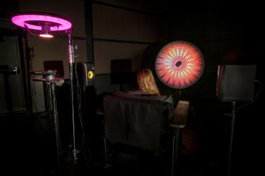 installation view of resonant waves showing camera behind chair, stereo speaker setup, with viewer in chair observing visual projection