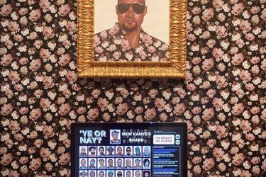 Desktop computer in a gallery installation, showing digital game Ye or Nay, in front of a floral wallpaper and portrait of Kanye west in matching floral shirt